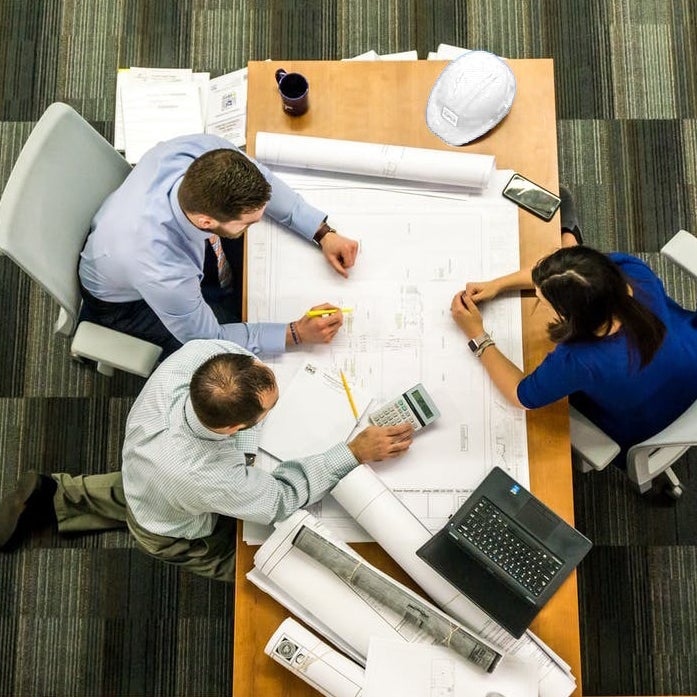 engineers sitting around a table looking at blueprints