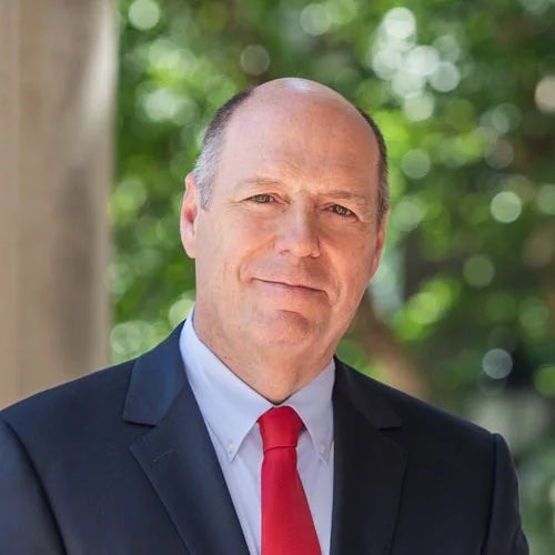 a balding man wearing a blue jacket and red tie