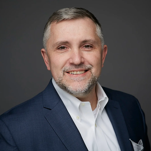 a middle-aged man with salt and pepper goatee in a blue blazer and white shirt