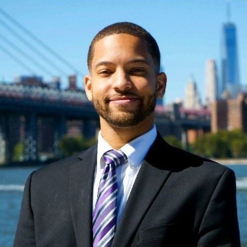 photo of a man wearing a suit with the a city skyline in the background