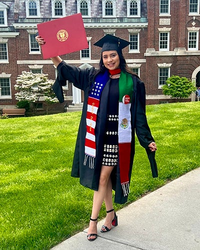 woman in college graduation garb holding a diploma up