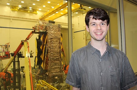 man in front of the inner components of a space telescope